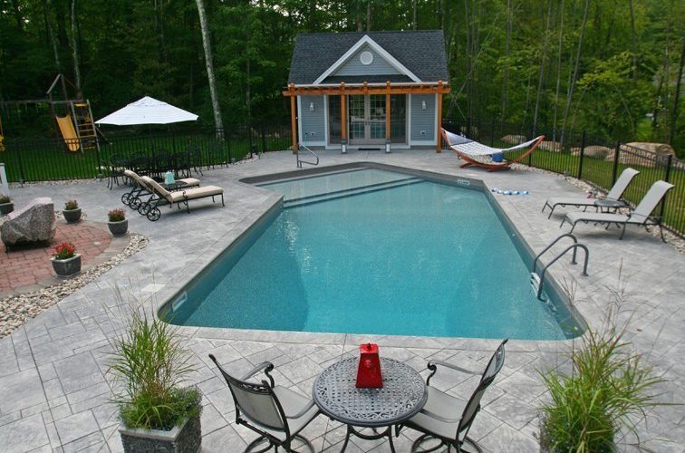This is a photo of a Lazy L style inground swimming pool with custom pool house and pool furniture.