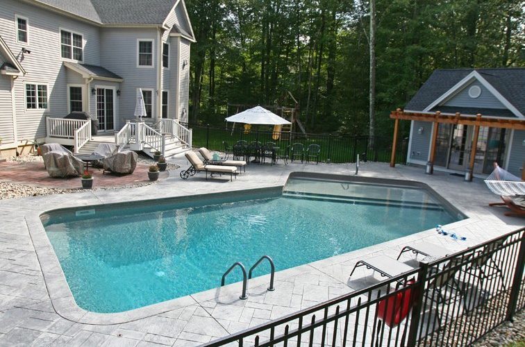 This is a photo of a Lazy L style inground swimming pool with custom pool house and furniture.