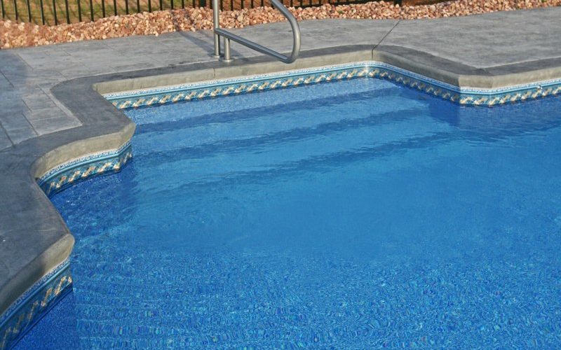 This is a photo of a roman in ground pool in Kinderhook, NY with custom pavers, diving board and steps.